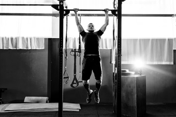 Muscular bearded man training his biceps and back in gym. Pull-ups. Workout lifestyle concept