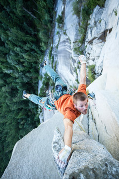 climber dangling from cliff by one hand