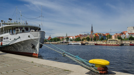 CITY ON THE RIVER - Small ship moored at the embankment of a promenade © Wojciech Wrzesień