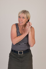 portrait of a attractive blond haired mid aged european woman wearing blue striped top acting with cellular phone - studio shot on white background.