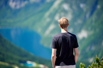 Junger Mann steht auf einem Berg und schaut in das Tal