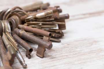 A bunch of old rusty keys on a white wooden table