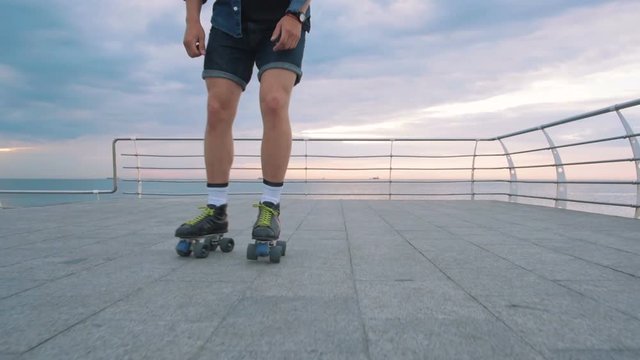a young caucasian man roller skating with quad skates near the sea, slow motion