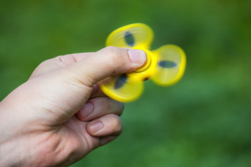 Teenager is playing a yellow spinner in her hand outdoors.