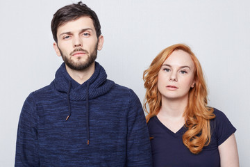 Redhead freckled Caucasian woman standing shoulder to shoulder to brutal brunette handsome friend.