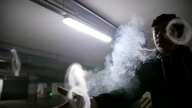 Young vaper produces tricks with steam rings