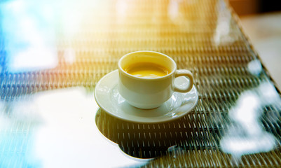 A cup of coffee in the morning in the sun on a glass table