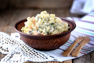Traditional Russian salad Olivier on an old wooden background. Russian kitchen. Rustic style.