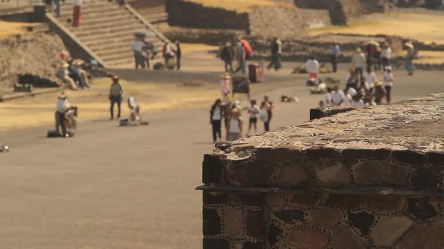 Avenue of the Dead in the Mayan city Teotihuacan. Details of one of the Mayan pyramids in the foreground, walking tourists in the background
