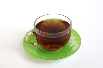 glass Cup with tea on a green saucer on a white background