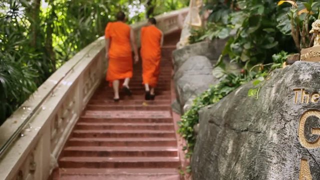 Two monks in orange robes walk up the stairs at Wat Saket (Golden Mount). Bangkok, Thailand.