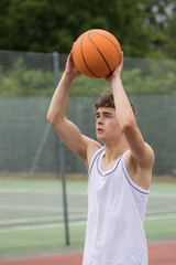 Teenage boy shooting a hoop on a basketball court