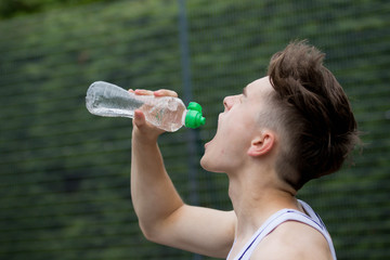 Teenage boy squirting water into his mouth