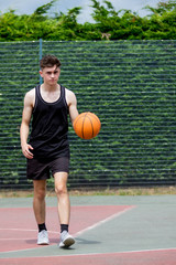 Teenage boy bouncing a basketball on a court