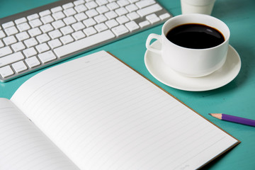 office table with notebook, computer keyboard, cup of coffee and notebook copy space