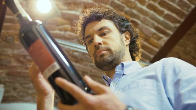 Caucasian man with curly hair choosing wine in the supermarket. Close up. View from the bottom.