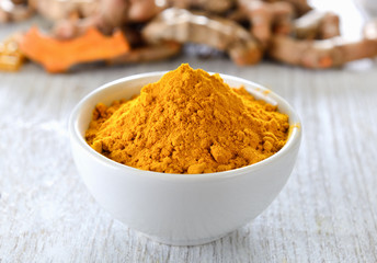 Turmeric powder in white cup on wooden