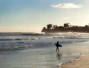 Surfer leaving waves at sunset on windy day