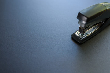 Closeup of a stapler isolated on grey background. - obrazy, fototapety, plakaty