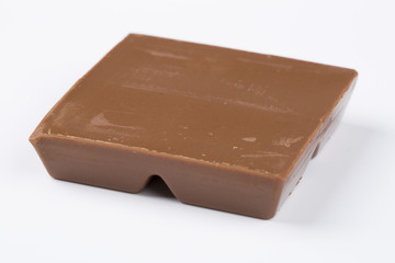 One square piece of chocolate, isolated on white.