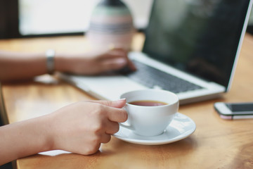 Close Up of woman hands using mobile phone and laptop computer with blank copy space screen for your advertising text message or content business in the Vintage effect.
