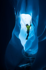 Ice climber viewed through a tunnel in the bottom of a moulin on the Matanuska Glacier in Alaska