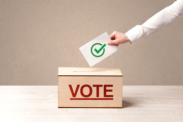 Close up of male hand putting vote into a ballot box