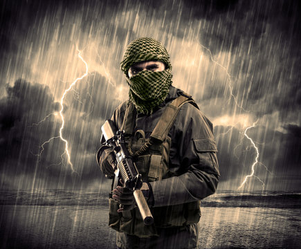 Dangerous armed terrorist with mask and gun in a thunderstorm with lightning