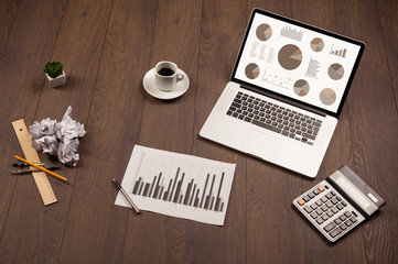 Pie chart graph icons on laptop screen with office accessories