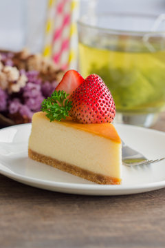 Homemade New York cheesecake on white plate decorated by strawberry and parsley. Moist and smooth classic style baked cheesecake. Copy space background of delicious strawberry New York cheesecake.