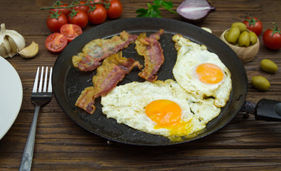 Fried eggs and bacon in the frying pan. Gourmet breakfast