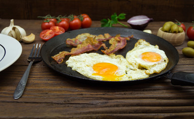 Fried eggs and bacon in the frying pan. Gourmet breakfast