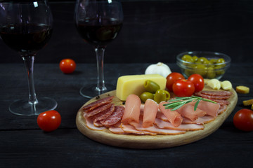 Appetizer on a wooden board with wine and olives for two