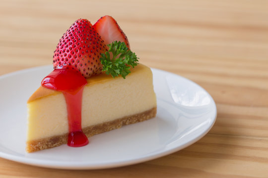 Homemade New York cheesecake on white plate decorated by strawberry,parsley and strawberry sauce. Moist and smooth classic baked cheesecake. Copy space background of delicious New York cheesecake.