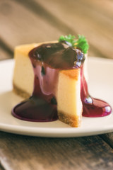Homemade blueberry cheesecake on white plate decorated with parsley and blueberry sauce. Moist and smooth classic baked cheesecake. Copy space background of delicious blueberry New York cheesecake.
