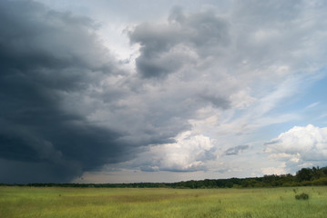 Storm cyclone over summer fields and forests