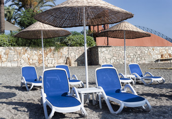Empty deckchairs and umbrellas with a thatched roof on the beach in Turkey