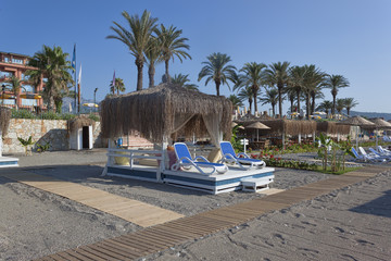 Place on the beach with sun beds and a gazebo with a thatched roof