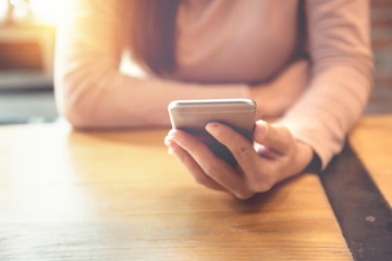 Woman hand holding smartphone at modern coffee shop, She watching video on mobile phone.