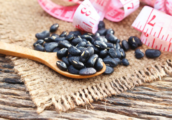 Close up black bean on spoon wood table background.Concept of organic food,