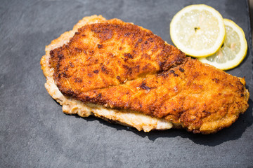 Cordon bleu mit Zitrone angerichtet auf einer Schiefertafel