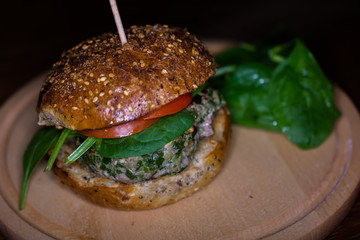 Rustic Beef Spinach Feta Cheese Burger With Tomatoes Served on a Woden Board With Baby Spinach Garnish