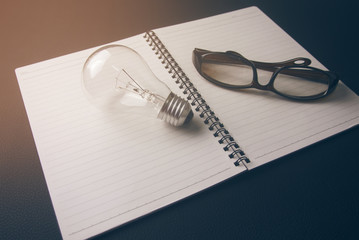 note paper book with light bulb and eyeglasses