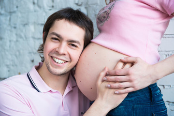 Fototapeta premium Pregnant couple hugging woman belly, close up happy smile husband listening to thr pregnant woman belly.
