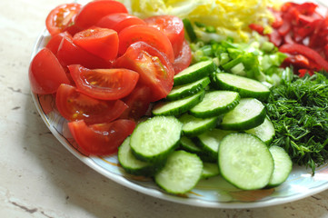 Fresh organic sliced vegetables on the white plate on the wooden table. Close up, selective focus.