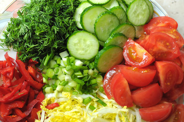 Fresh organic sliced vegetables on the white plate on the wooden table. Close up, selective focus.