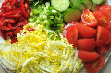 Fresh organic sliced vegetables on the white plate on the wooden table. Close up, selective focus.