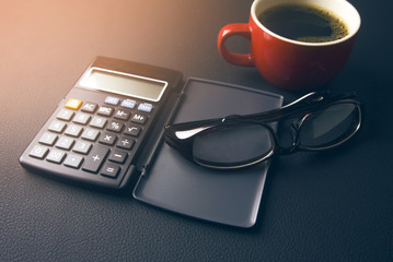 coffee and calculator with eyeglasses on desk