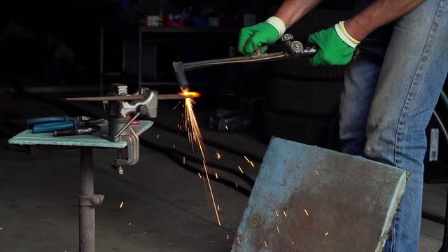 Worker cuts the metal with a retro cutter in a small workshop