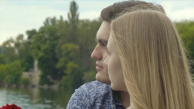 Young beautiful couple on a date standing on a bridge by the lake